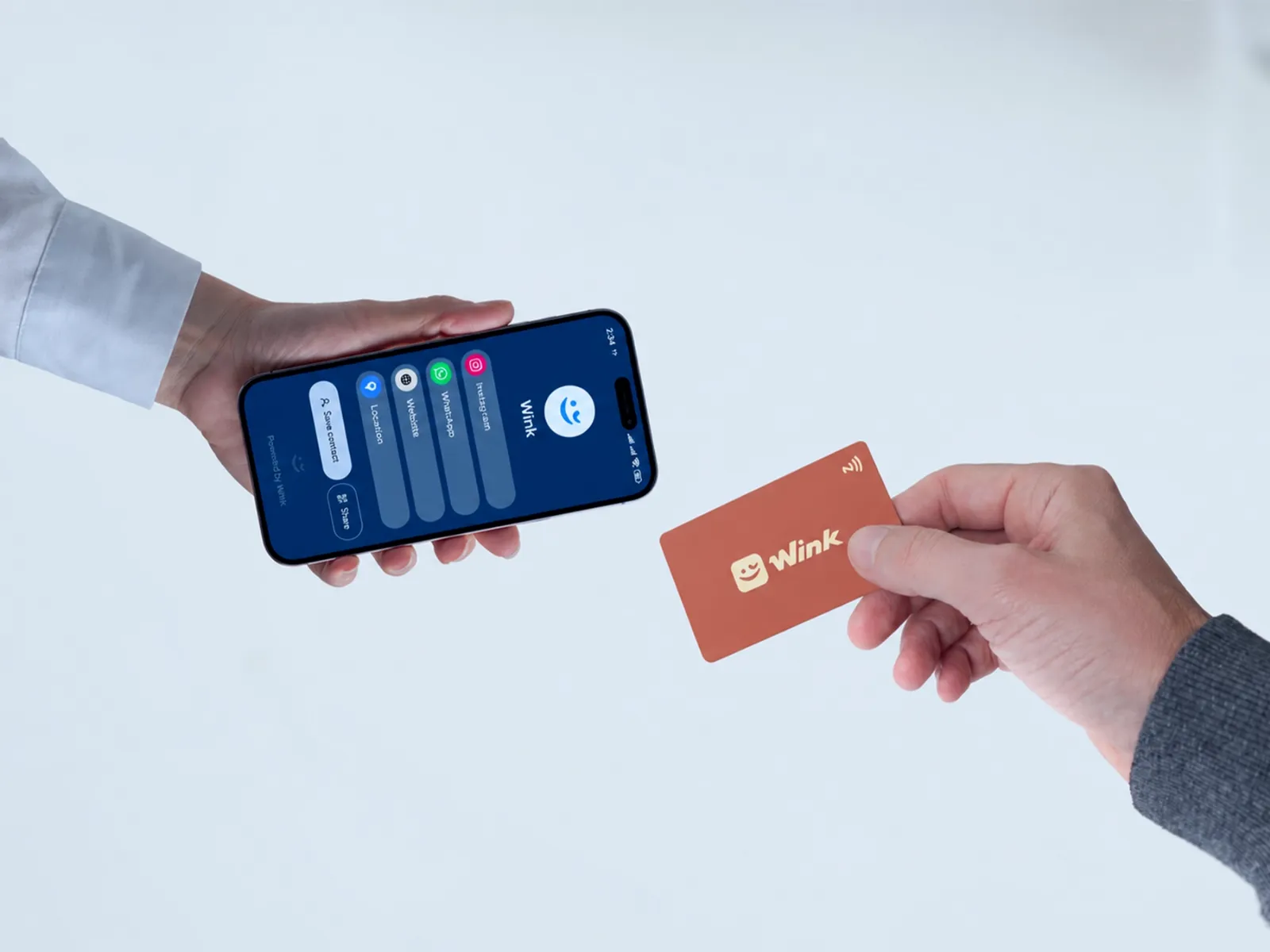 Two people meeting at a café or office in Erbil; one taps a Wink card on the other's phone